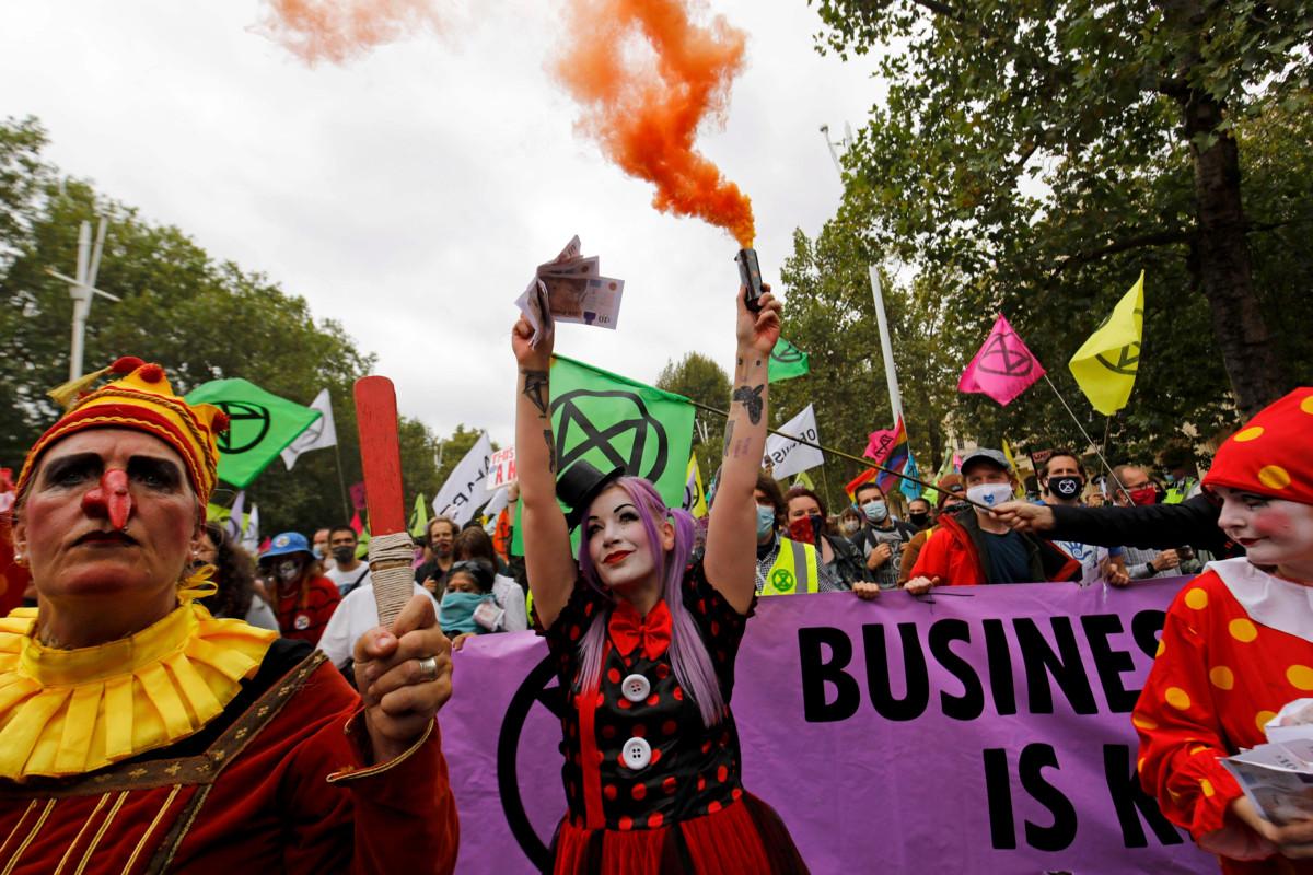 Aktivisti heilutti leikkirahaa ja soihtua Extinction Rebellion -liikkeen mielenosoituksessa Lontoossa syyskuun alussa. Kuva: Tolga Akmen Lehtikuva/AFP