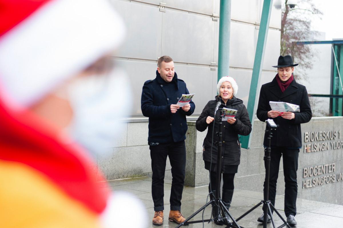 Jarno Kokko (vasemmalla), Mia Heikkinen ja Anton Mellanen lauloivat keskiviikkona 25. marraskuuta joululauluja Viikin yliopistokampuksen Biokeskus ykkösen portailla.