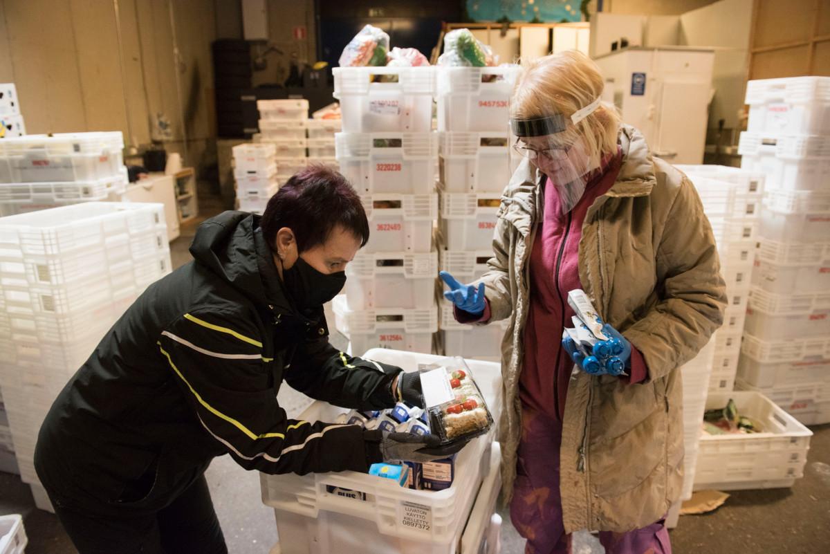 Vakituinen työntekijä Eija Vahtera ja TE-toimiston työkokeilussa oleva Lotta Oksa jakavat elintarvikkeita Myllypuron ruoanjakelupisteellä. 