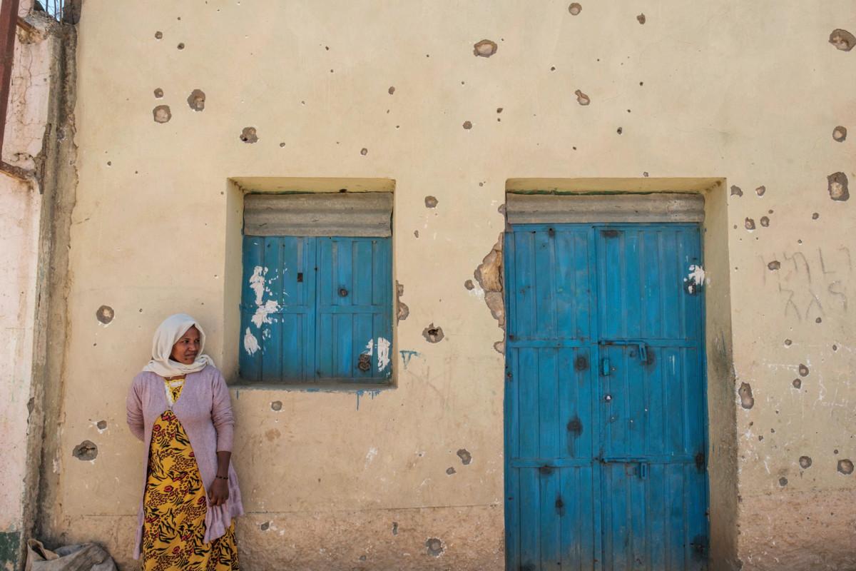 Nainen nojaa tulituksessa pahoin vaurioituneen talon seinään Wukrossa. YK:n mukaan monin paikoin asukkaita uhkaa nälänhätä. Seksuaalista väkivaltaa käytetään Tigreyn sodassa aseena.