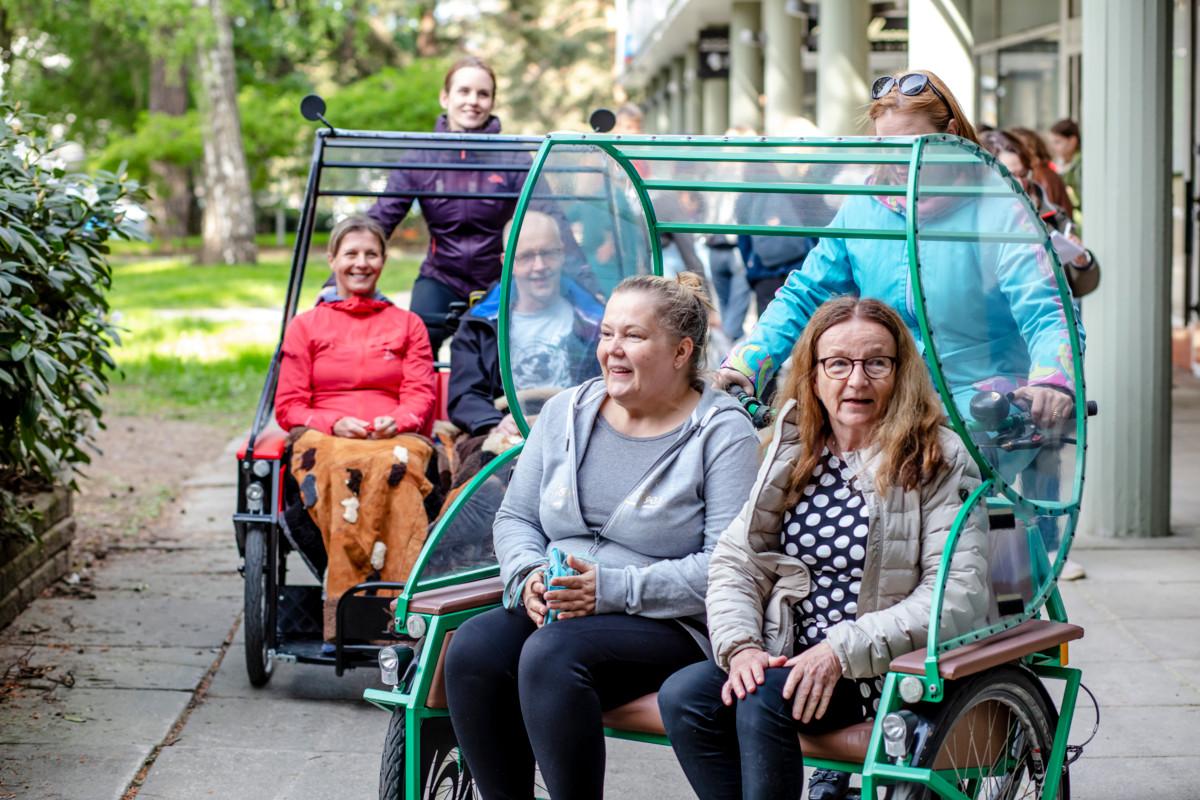 Pyöräluotsikurssilaiset Sanna Pajulo, joka on vasemmanpuoleisen riksapyörän ohjaimissa, ja Marianne Tiihonen harjoittelevat riksapyörällä ajamista. Pajulon kyydissä istuvat Jaana Rossi ja Juha Rouhiainen. Etualalla Tiihosen kyydissä ovat Sini Raiko ja Maritta Kopsala.