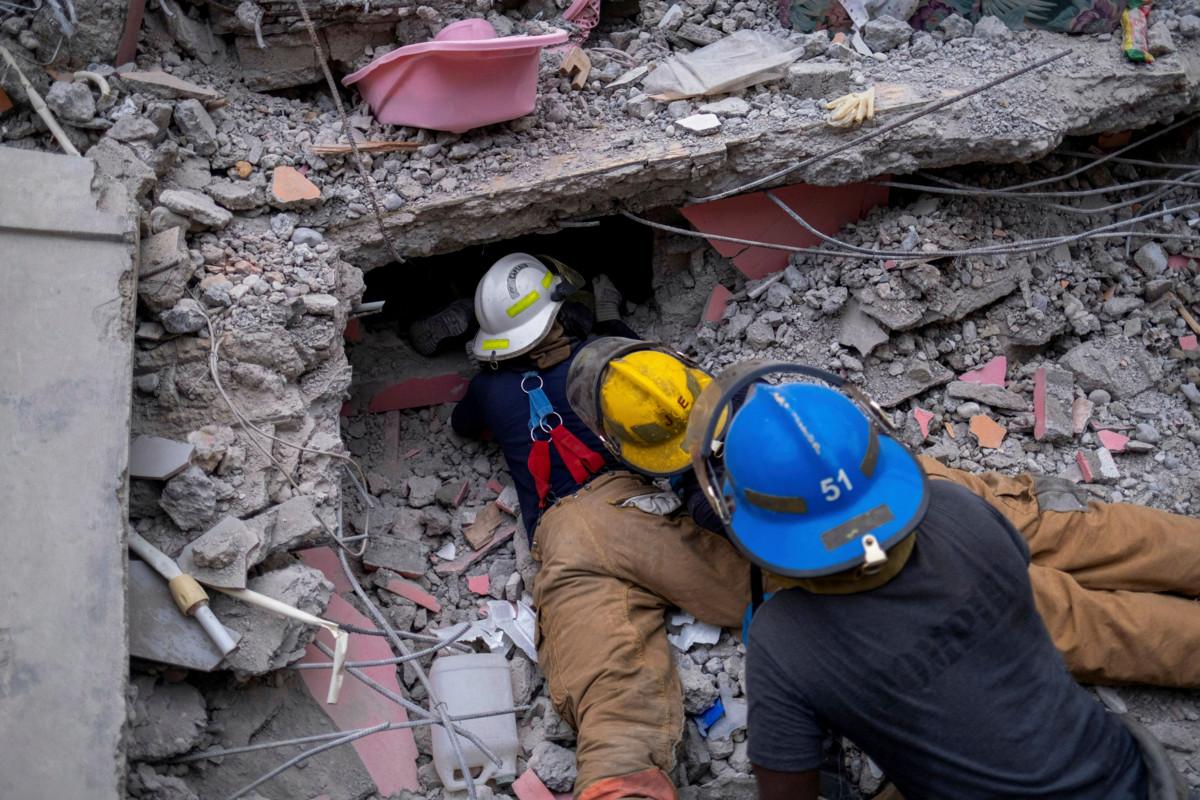 Palomiehet etsivät henkiinjääneitä maanjäristyksessä tuhoutuneen hotellin raunioista Les Cayesin kaupungissa Haitissa.