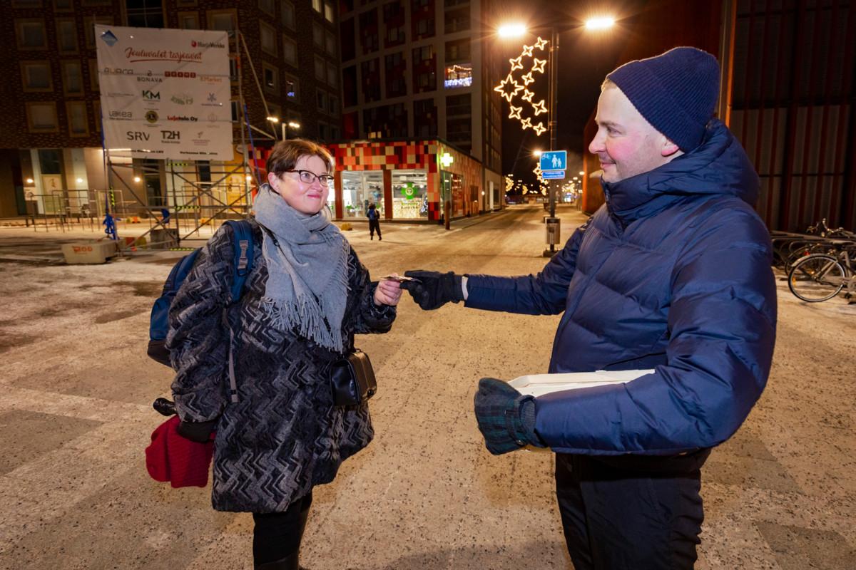 Pappi Aki Kekkonen antaa heijastimen Tarja Äijölle.