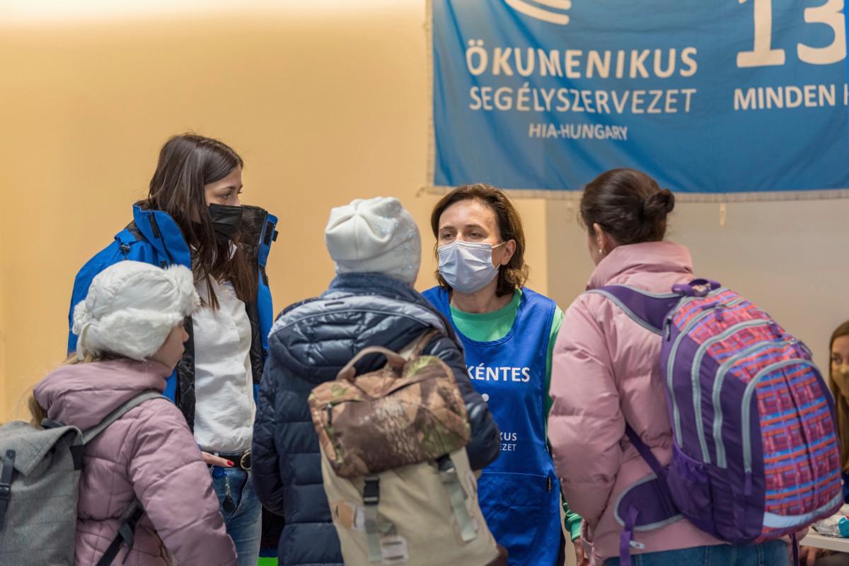 Vapaaehtoistyöntekijä Karolina Burcs opastaa pakolaisperhettä Unkarin kirkkojen välisen avun (HIA) perustamassa tukikeskuksessa Budapestin lentokentällä. Keskuksen työntekijät auttavat pakolaisia, joiden täytyy usein odottaa kentällä lentoja jopa päiväkausia. Pakolaisilla annetaan ruokatarvikkeita ja leluja ja heille järjestetään myös majoitusta lähistön hotelleissa.