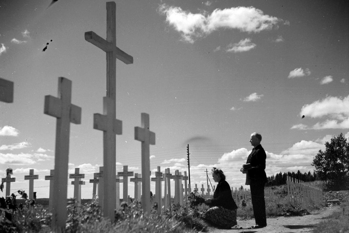 Evakkomatkalle lähtevät isä ja tytär lähisukulaisensa sankarihaudalla Suistamolla vuonna 1944.