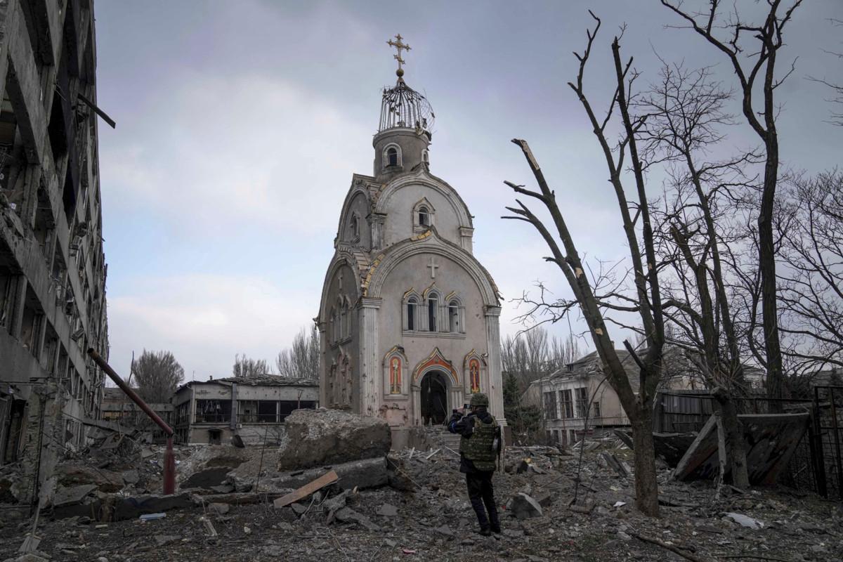 Ukrainalainen sotilas ottaa valokuvaa Venäjän pommitusten jäljiltä vaurioituneesta kirkosta Mariupolissa Ukrainassa. Kuva: Evgeniy Maloletka / AP / Lehtikuva