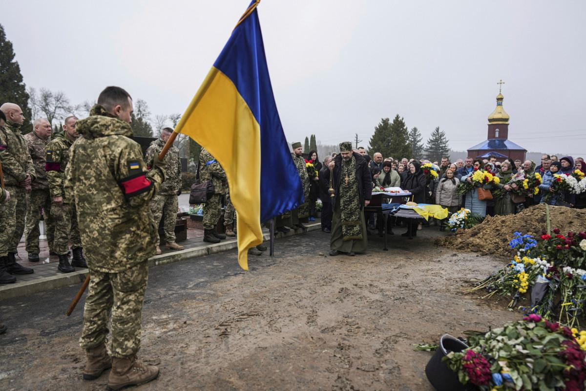 Ukrainalaisia hautaamassa taistelutoveriaan lähellä Lutskin kaupunkia. Kuva: Evgeniy Maloletka/AP/Lehtikuva