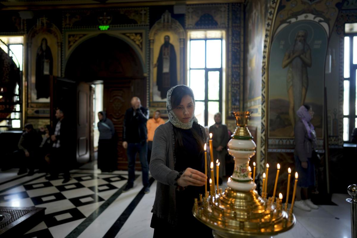 Nainen sytyttää kynttilää luostarikirkossa Kiovassa. Moskovan patriarkaattiin kuuluva Ukrainan ortodoksinen kirkko ilmaisi toukokuun lopussa halunsa itsenäistyä. Taustana tähän on Venäjän hyökkäyssota. Kuva: Natacha Pisarenko/AP/Lehtikuva