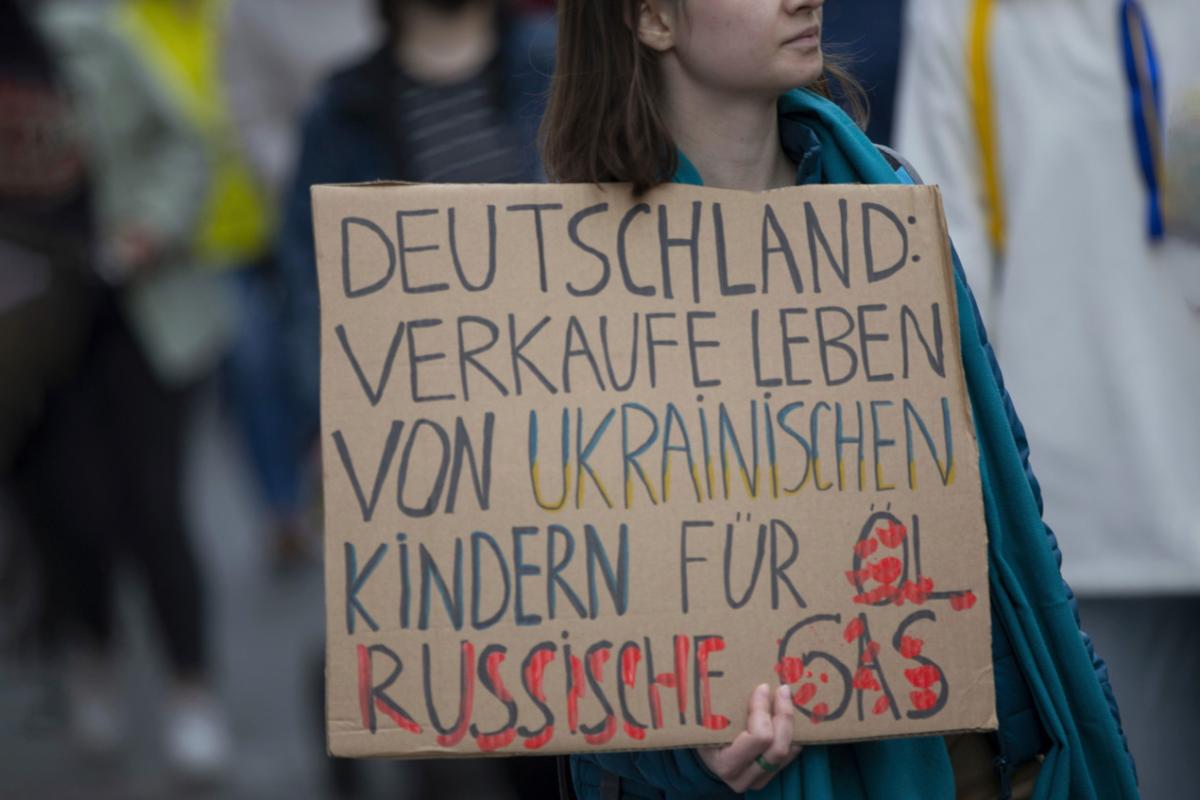 Saksalainen mielenosoittaja Ukrainan sodan vastaisessa mielenosoituksessa. Kyltissä todetaan, että Saksa myy ukrainalaislasten hengen vastineeksi veväläisestä öljystä ja kaasusta.