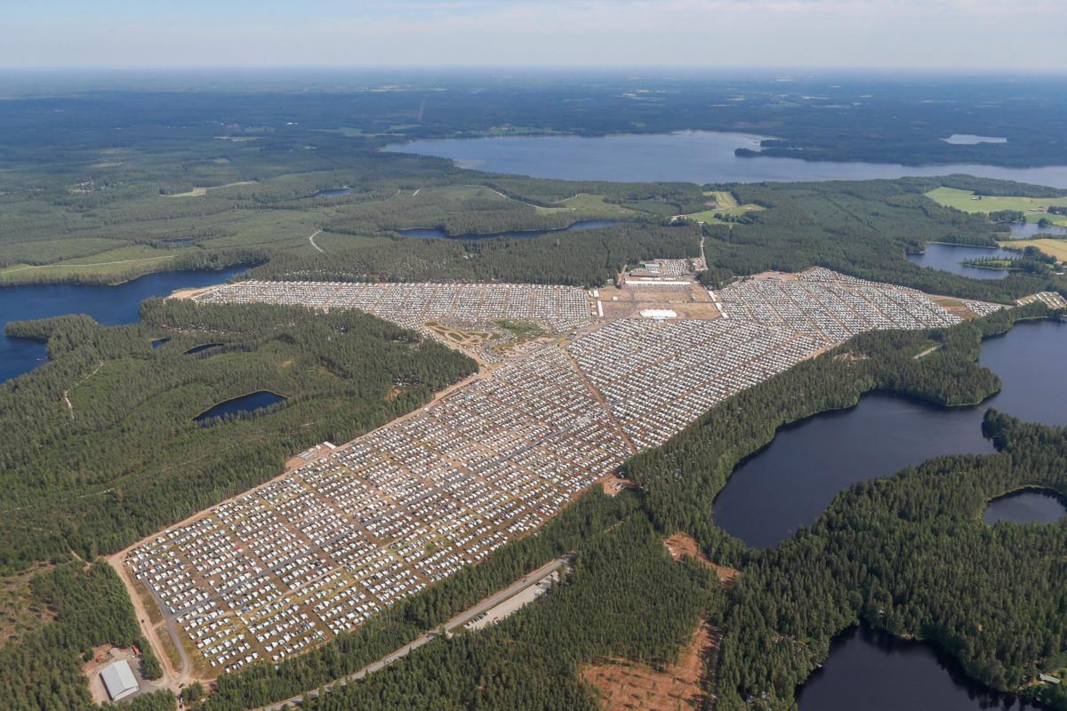 Valtava lentäkenttäalue oli täynnä asuntovaunuja ja autoja. Juhlateltta ja sitä ympäröivä aukio näkyvät kuvat ylälaidassa. Kuva: Suviseurojen kuvapalvelu