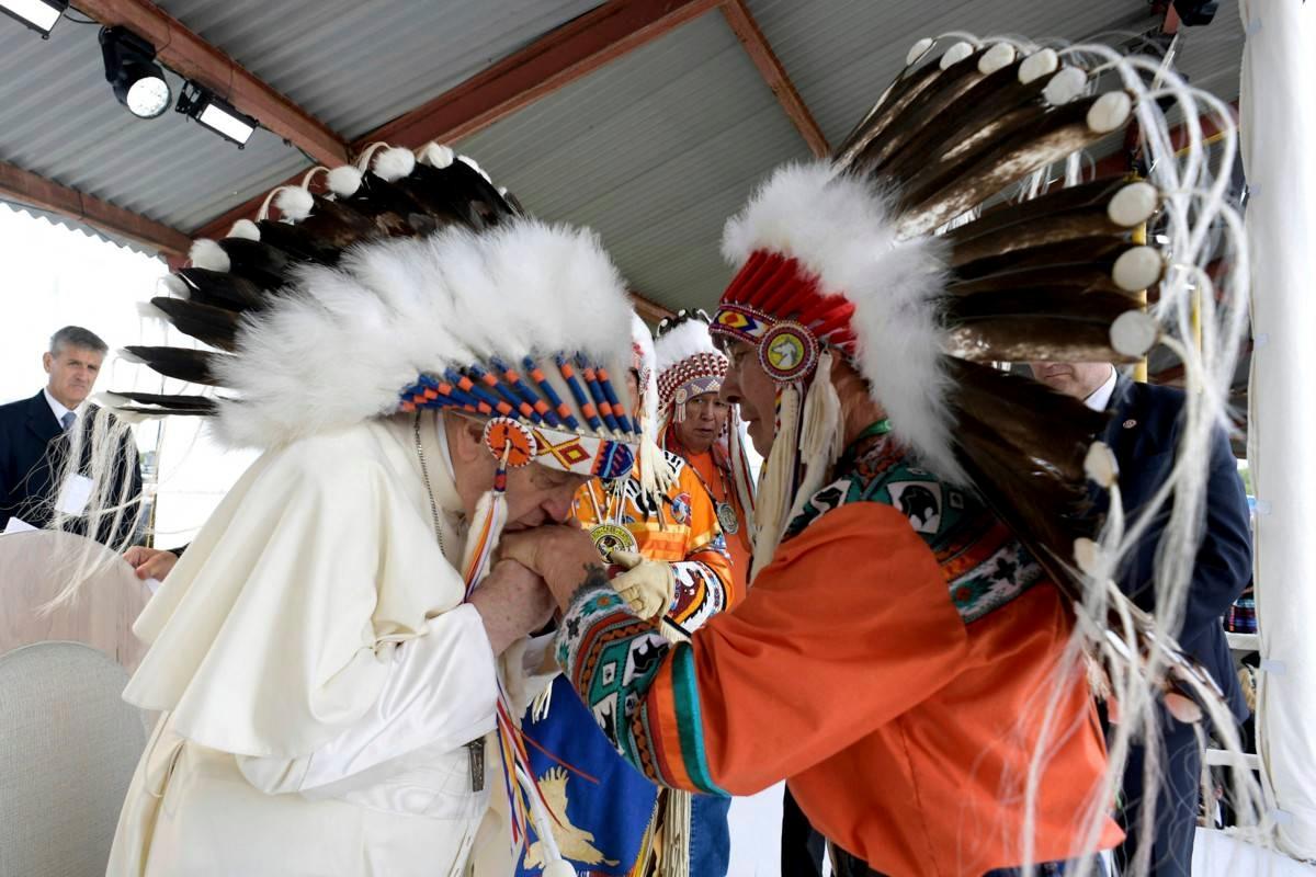 Paavi Franciscus tervehtii alkuperäiskansojen edustajia lahjaksi saamassaan päähineessä Maskwacisissa, Länsi-Kanadassa. Siellä paavi piti odotetun puheensa.