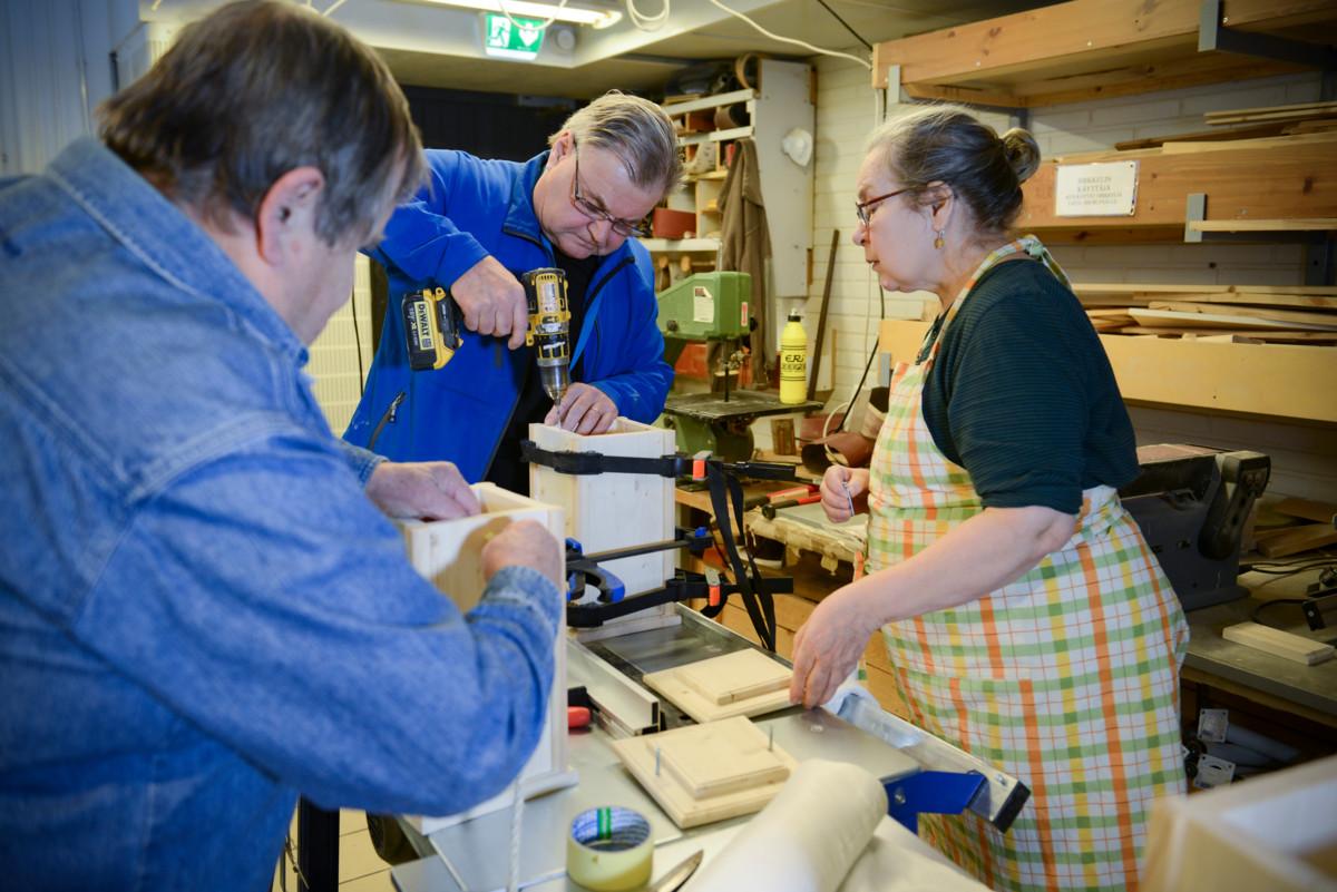 Tauno Karvosenoja, kurssin vetäjä Pekka Tähtinen ja Satu Helistö työn touhussa Hermannin diakoniatalon verstaalla.