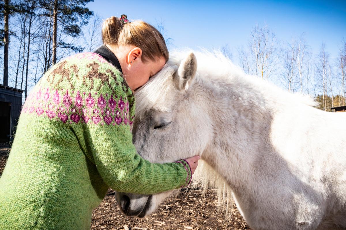 Psykologi, psykoterapeutti Anna-Kaisa Pitkänen halaa Eir-nimistä islanninhevosta Breytingin terapiatilalla.