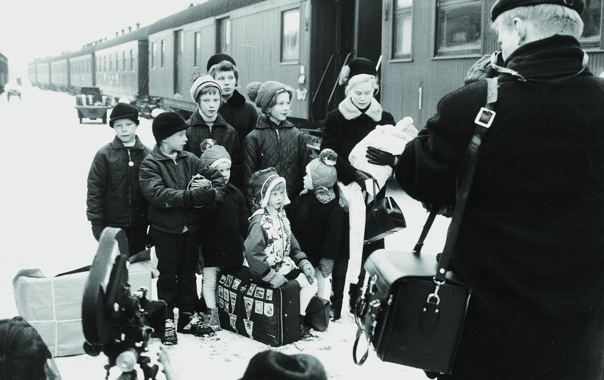 Lehdistö oli vastassa, kun Pentikäisen sisarukset saapuivat Helsingin rautatieasemalle yön yli kestäneen junamatkan jälkeen. Raija on kuvassa takimmaisena, nuorin veli kodinhoitajan sylissä. Kuva: SOS-lapsikylä/tiedotus