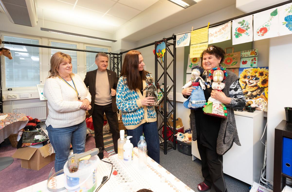 Tanja Mustonen (vas.), Vassili Goutsoul ja Nadiya Maksymyuk ihailevat Nadiya Abzon tekemiä motanka-nukkeja Helsingissä sijaitsevassa ukrainalaisten avustuskeskuksessa.