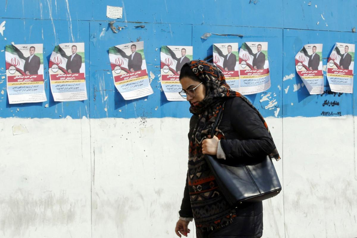 Nainen kävelee parlamenttivaalien ehdokkaita esittävien julisteiden ohitse. Kuva: AFP/Lehtikuva