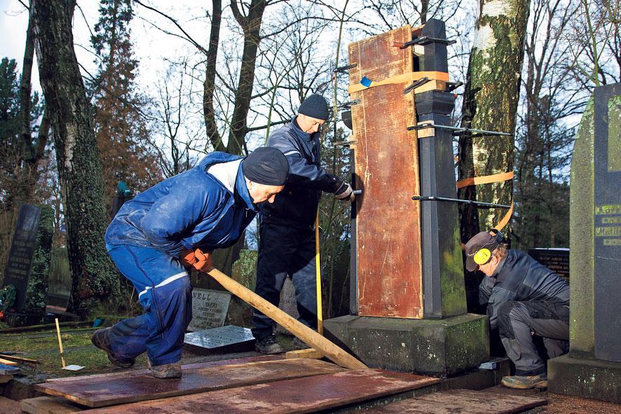 Hautamuistomerkki pystyyn. Hietaniemen hautausmaalla muun muassa Pertti Johansson ja Eino Ylönen olivat mukana pystyttämässä puiden juurten kallistamia hautakiviä. Tapaninpäivän myrsky kaatoi Hietaniemessä 25 puuta, joista viisi kumosi mukanaan myös hautamuistomerkin. Kuva: Esko Jämsä