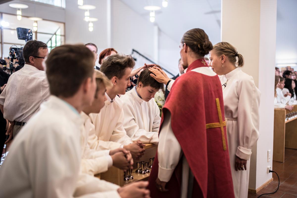 Pappi Lauri Holma ja nuorisotyönohjaaja Jonna Peitso siunaavat nuoret yhdessä kummien tai muiden läheisten aikuisten kanssa.