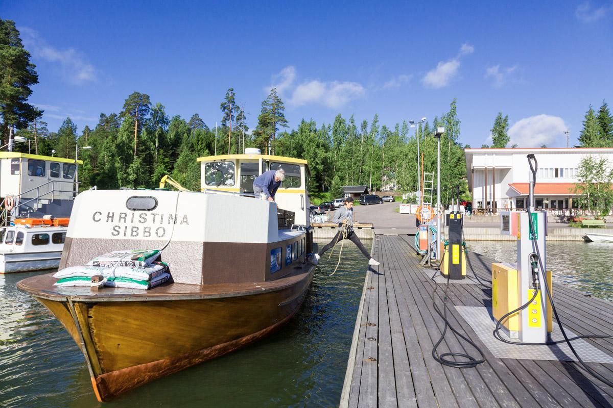 Kahdeksalta aamulla kauppalaiva Christinan lähtövalmistelut ovat jo hyvässä vauhdissa. Aleksi Heinonen kiinnittää laivan bensiinipumppujen viereen. Kapteeni Ensio 