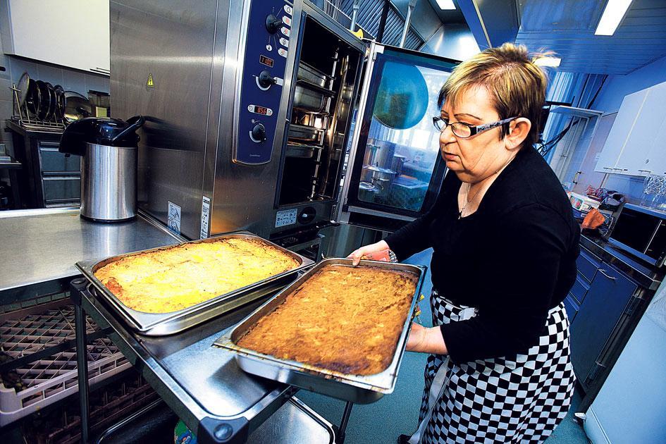 Rakkaudella tehtyä ruokaa. Myllypuron kirkon keskiviikkoruokailun vapaaehtoiskoordinaattori Sinikka Backman kiidättää lanttu- ja porkkanalaatikkoja uunista pöytään. Kuva: Esko Jämsä