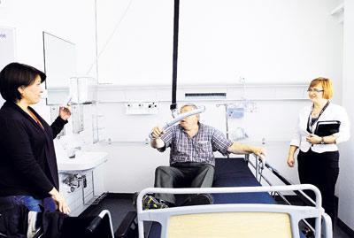 Kirsi Mustalammi (vas.) ja Eeva Rikkilä-Kettunen esittelivät Heikki Päivikkeelle potilaan nostamiseen tarkoitettua laitetta. Kuva: Natalia Baer