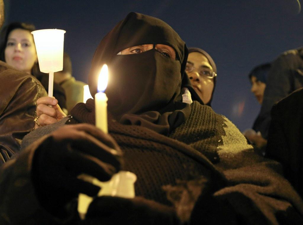 Egyptiläinen musliminainen pitää kynttilää koptikirkon edessä Kairossa. Kymmeniä kristittyjä kuoli kirkkoon tehdyssä iskussa joulukuussa. Kuva: Lehtikuva / Reuters