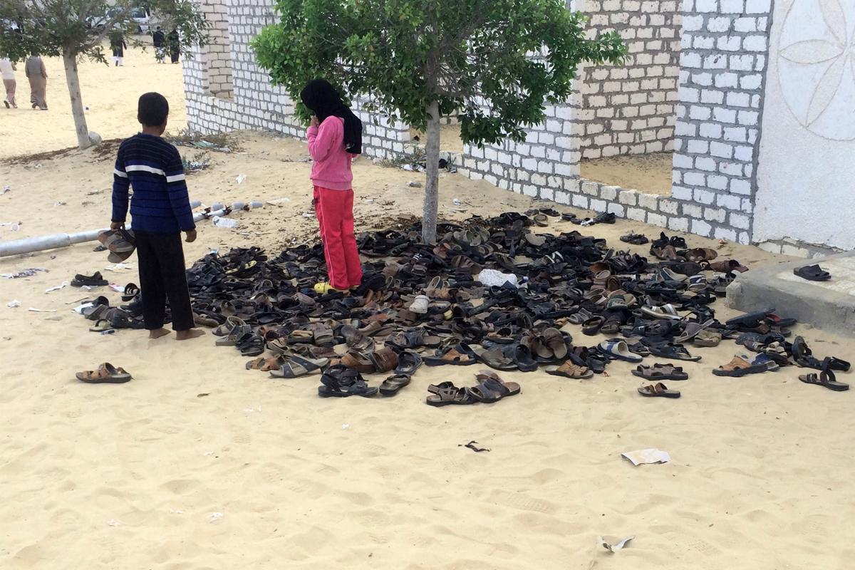 Lapsia seisomassa moskeijaan tehdyssa iskussa surmattujen ihmisten kenkäpinon vieressä.