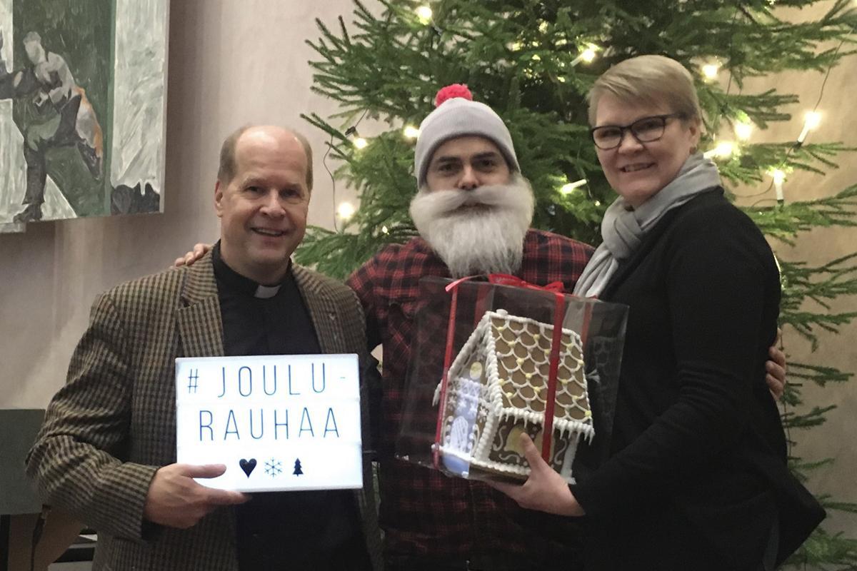 Kirkkoherra Martti Häkkänen ja vapaaehtoistoiminnan koordinaattori Katri Kulmala tapasivat Brother Christmasin Mikaelinkirkossa. Kiitokseksi lahjoituksesta he antoivat hänelle seurakuntalaisen tekemän piparkakkutalon.